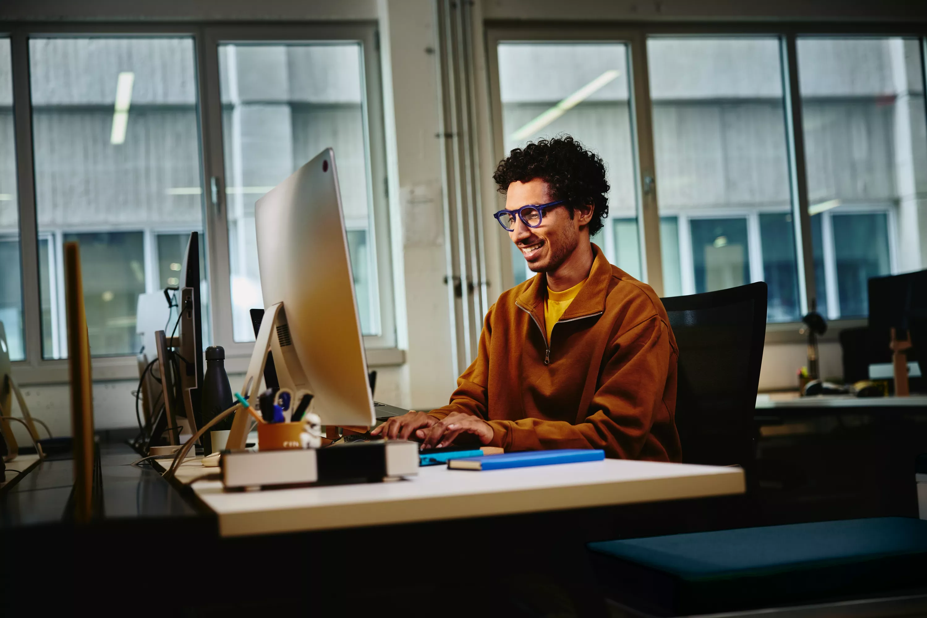 Mann sitzt am PC und lächelt