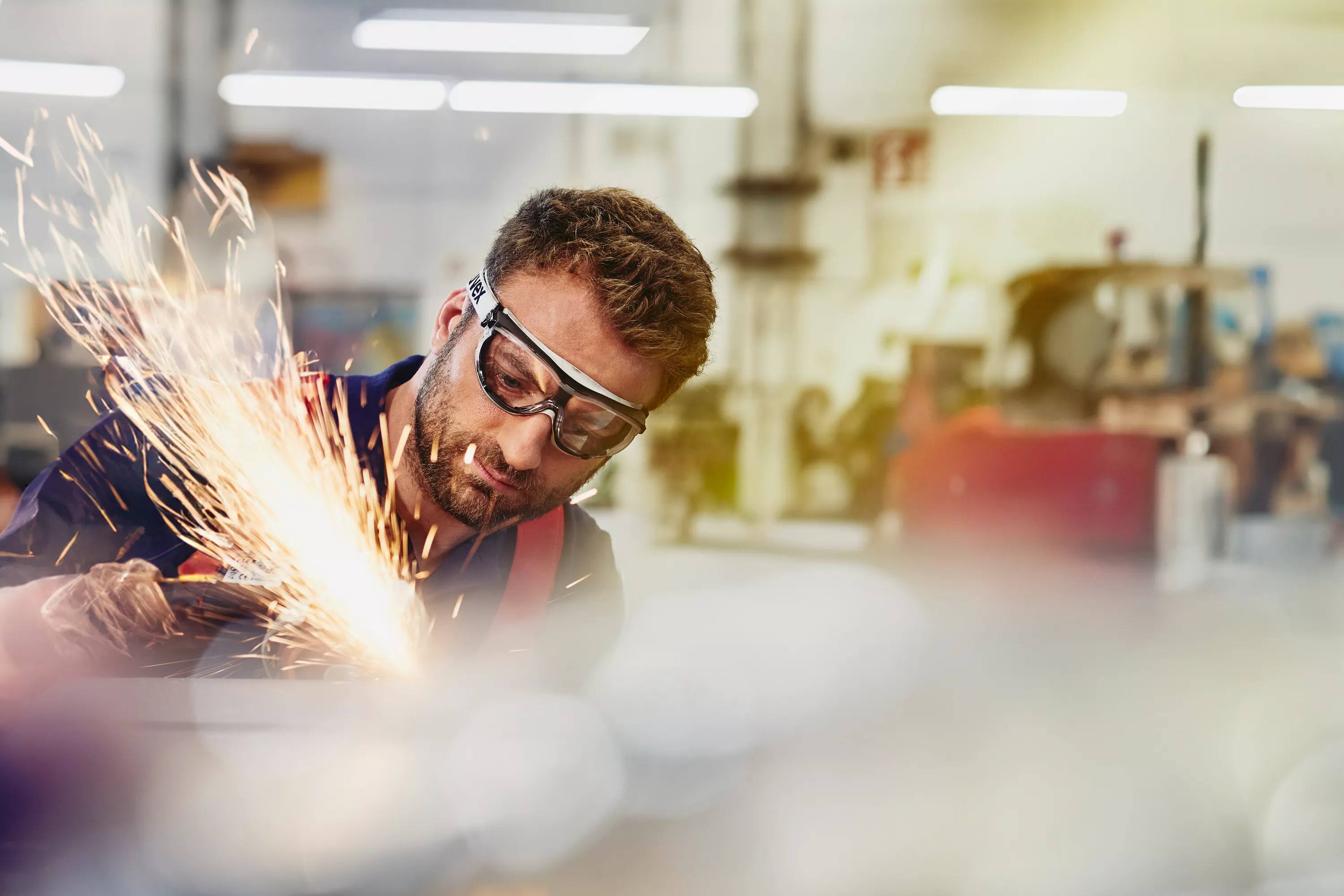  Mann trägt Schutzbrille und schleift Metall