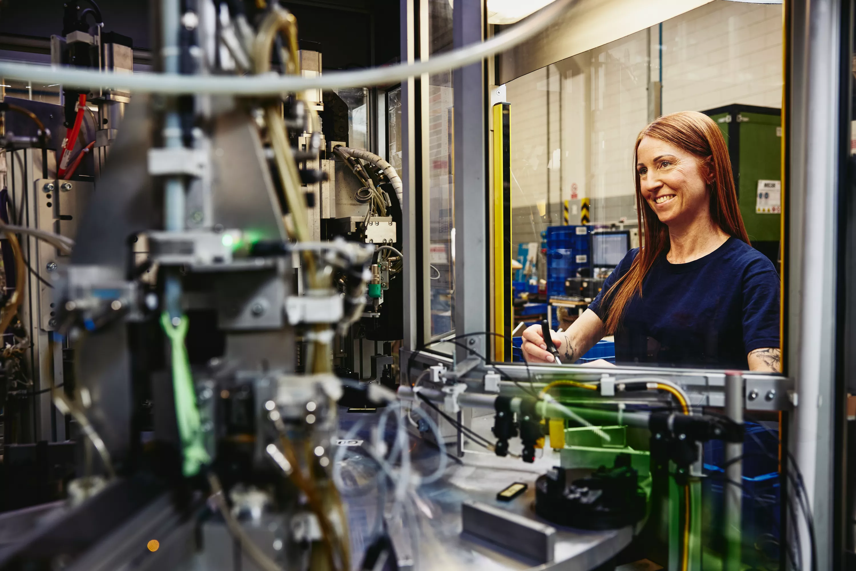 lächelnde Maschinenbedienerin beim Verrichten ihrer Arbeit