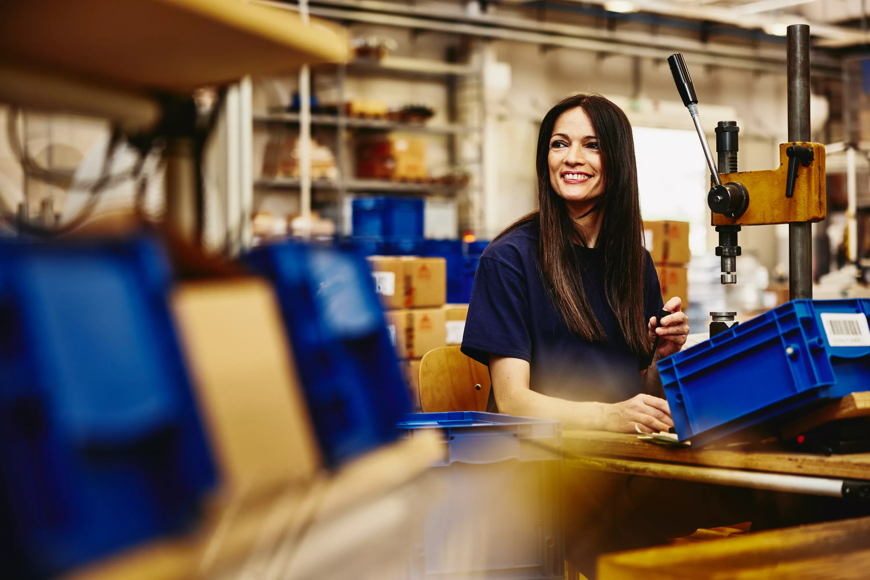 lächelnde Produktionsmitarbeiterin beim Verrichten ihrer Arbeit