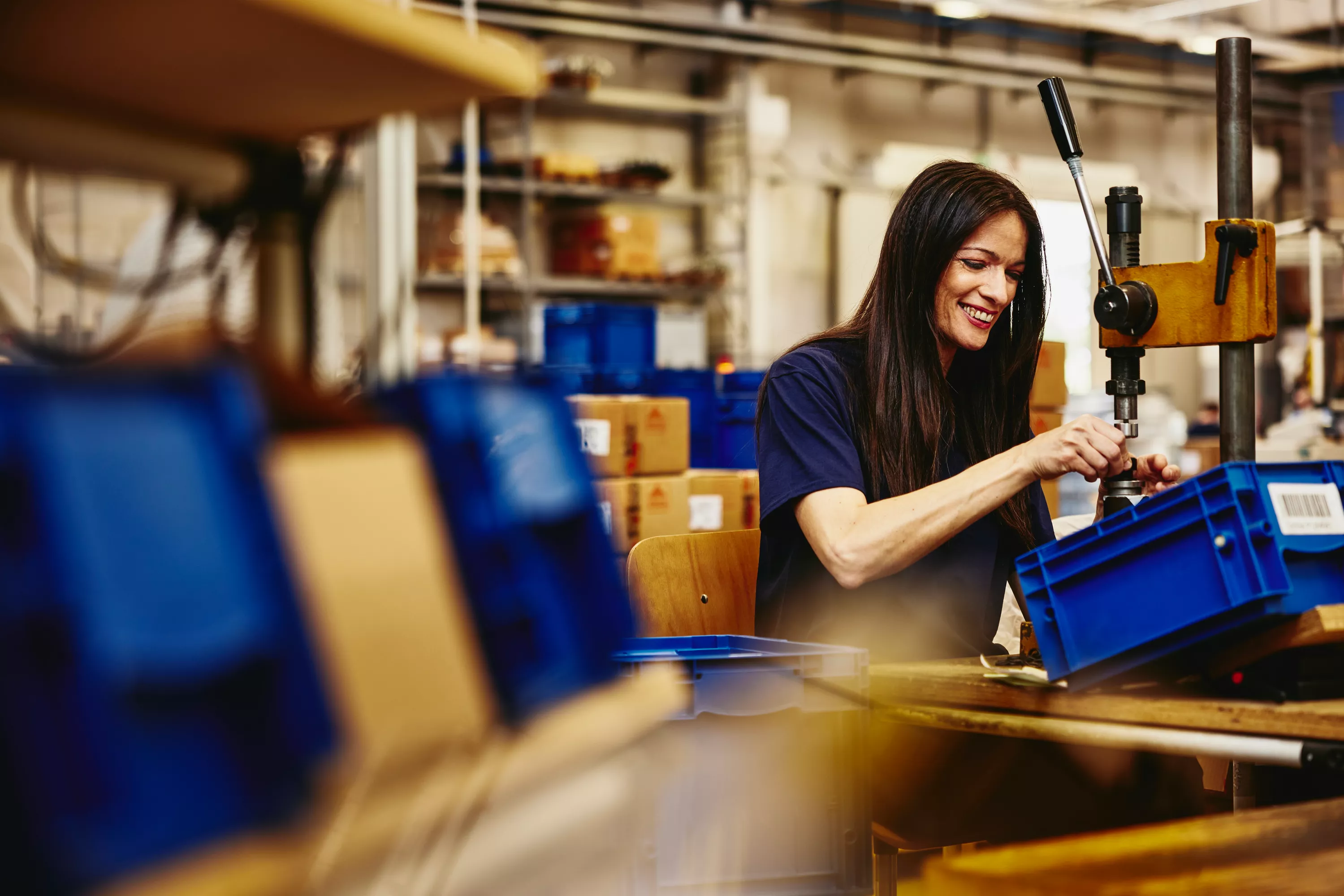 lächelnde Produktionsmitarbeiterin beim Verrichten ihrer Arbeit