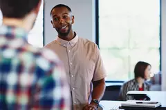 ein Mann lächelt den ihm in einem Büro gegenüberstehenden Mann an