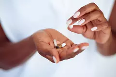 Nahaufnahme zweier weiblichen Hände, die Tabletten halten