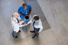 Vogelperspektive auf einen Geschäftsmann, der einem Arzt in einem Krankenhaus die Hand schüttelt